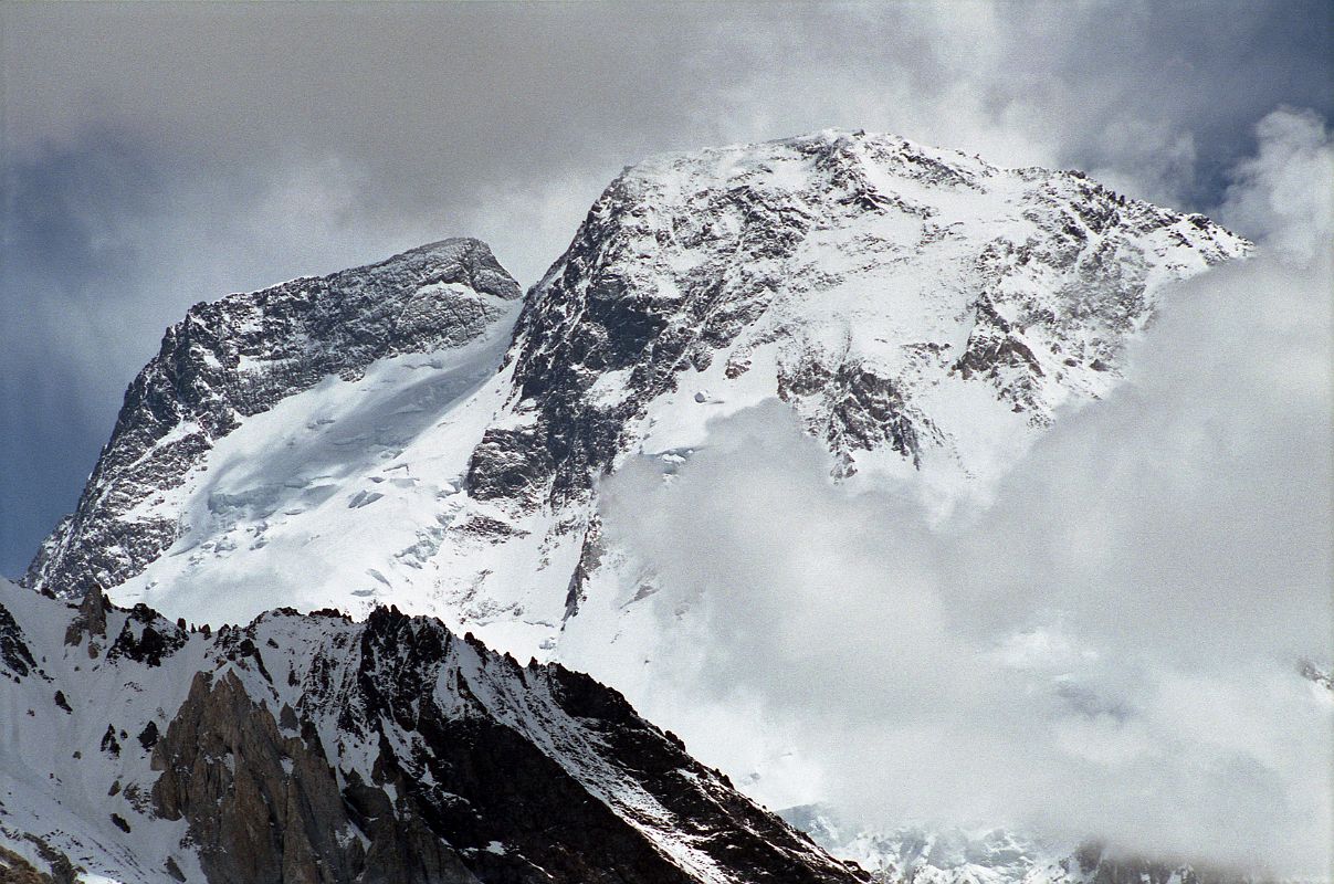 35 Broad Peak Central And Main Summits From Baltoro Glacier Between Goro II and Concordia Broad Peak (8047m) came into view before reaching Concordia. The Central Summit is on the left and the Main summit is on the far right. Its name was originally set as K3, right after the famed K2. But when Sir Martin Conway saw the peak in close detail, with its summit over a mile long, he named it Broad Peak which has stuck to this day. The first ascent of Broad Peak was completed by Marcus Schmuck, Fritz Wintersteller, Kurt Diemberger, and Hermann Buhl on June 9, 1957. This extremely small expedition marked a major step forward in the development of Himalayan climbing. Diemberger: [Buhl's] plan was that from base camp onwards there would only be climbers on the mountain; they would do everything, load-carrying, establishment of camps and, finally, the assault on the summit. And it was all to be done without the use of oxygen. Diemberger reached the summit just as Marcus Schmuck and Fritz Wintersteller started their descent. As Diemberger was descending from the summit he met Buhl still ascending. Slowly, with all that incredible strength of his will, he started to move, very slowly, upwards. ... Two men were standing on a peak, still breathing heavily from the ascent, their limbs weary - but they did not notice it; for the all-enveloping glory of the sun's low light had encompassed them too. Deeper and deeper grew the colours. ... No dream-picture, this. It was real enough, and it happened on the 26,404-foot summit of Broad Peak.  Summits And Secrets by Kurt Diemberger.